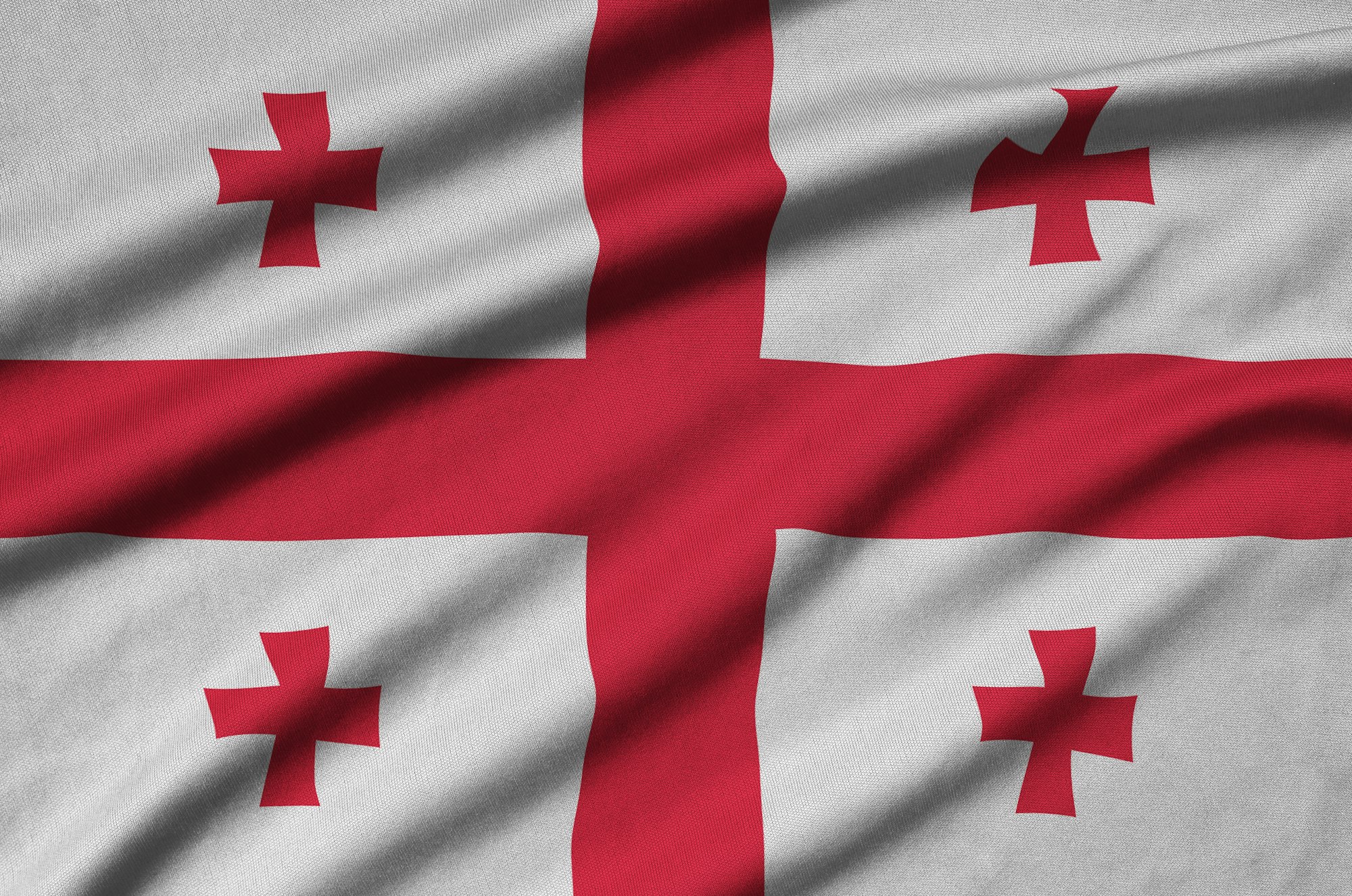 Georgia flag is depicted on a sports cloth fabric with many folds. Sport team waving banner