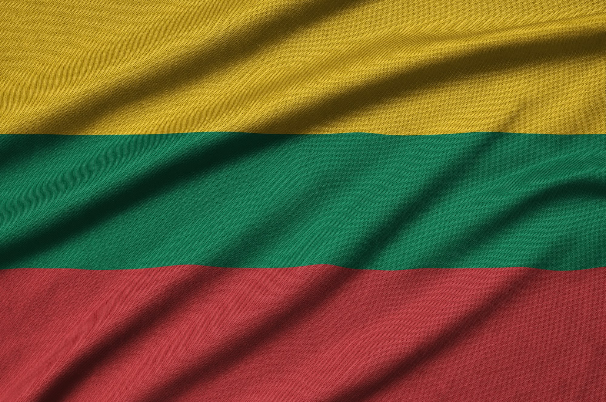 Lithuania flag is depicted on a sports cloth fabric with many folds. Sport team waving banner